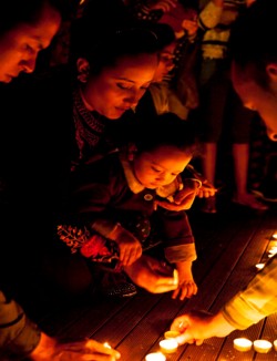 A family lighting candles together at a We Care Nepal vigil