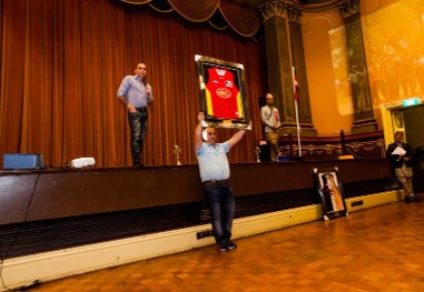 A framed item held up for bidding during the live auction at a charity dinner