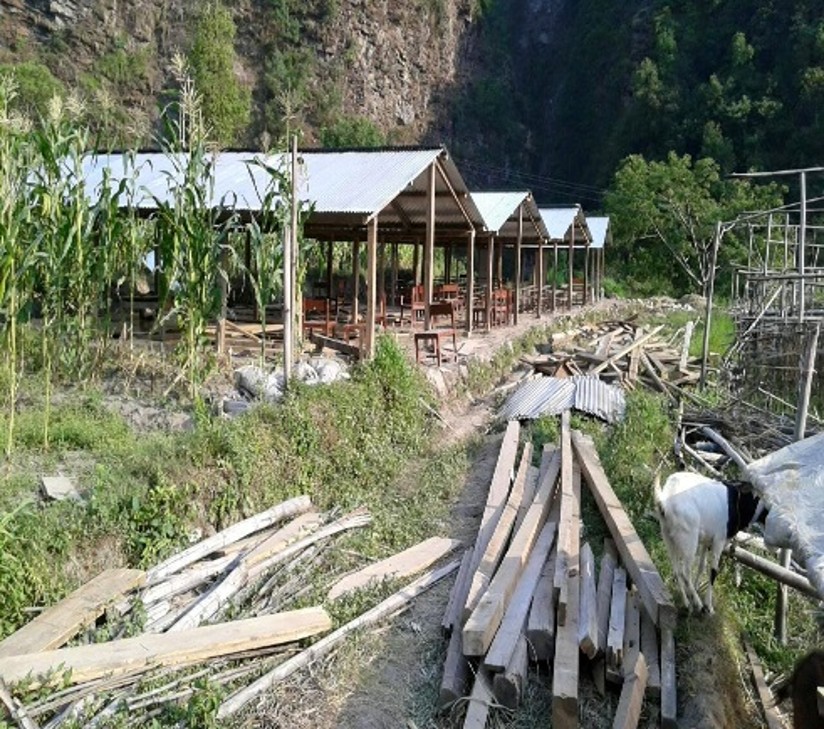Rebuilt classroom shelters with corrugated roofs on a hillside in Nepal